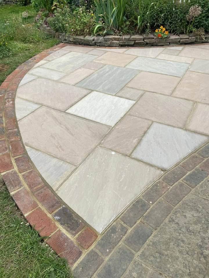 Curved sandstone patio with brick edging